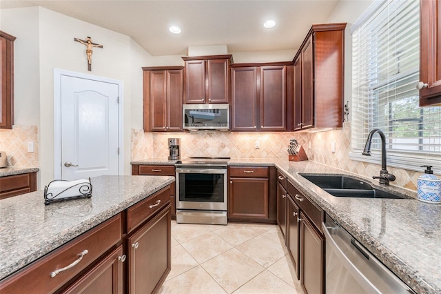 kitchen with light tile patterned floors, sink, backsplash, light stone countertops, and appliances with stainless steel finishes