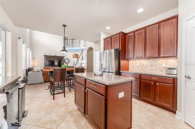 kitchen featuring light stone countertops, pendant lighting, appliances with stainless steel finishes, and a center island