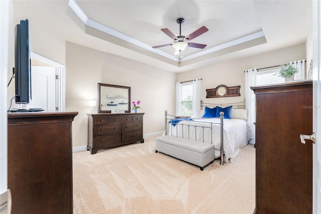 carpeted bedroom with ornamental molding, a tray ceiling, and ceiling fan