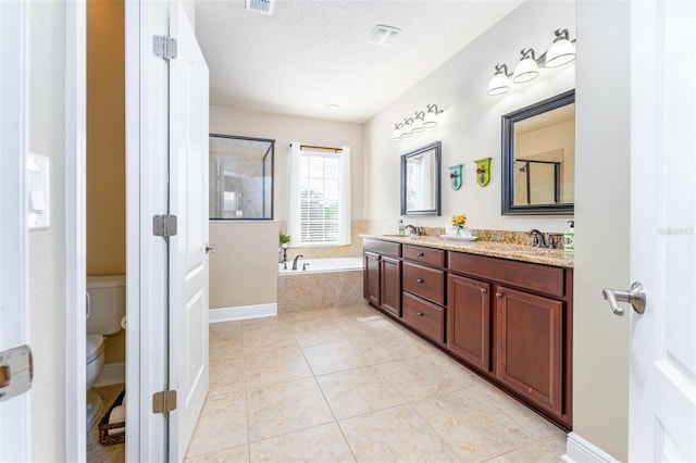 bathroom with tiled bath, vanity, a textured ceiling, tile patterned flooring, and toilet