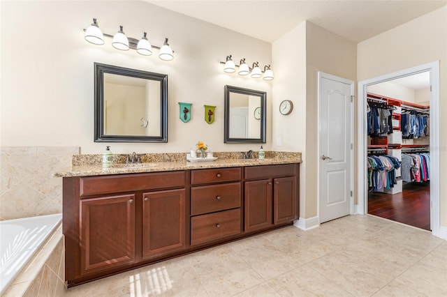 bathroom with vanity, tiled bath, and tile patterned flooring