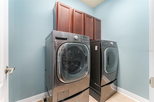 washroom with cabinets, light tile patterned floors, and washer and clothes dryer