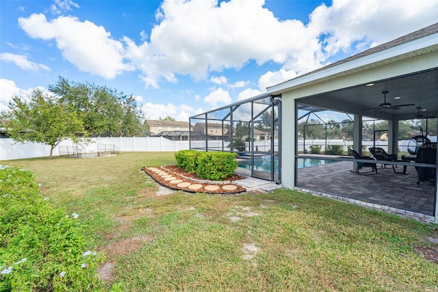 view of yard with glass enclosure, a patio, a fenced in pool, and ceiling fan