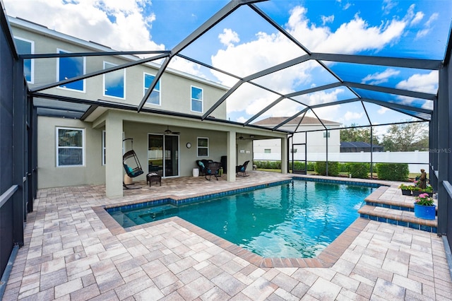 view of swimming pool with glass enclosure, a patio, and ceiling fan