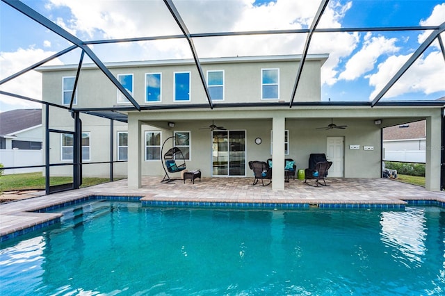 rear view of house with a lanai, ceiling fan, a fenced in pool, and a patio area