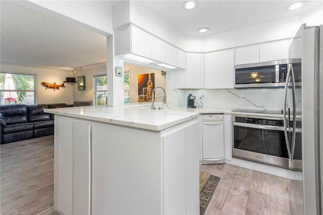 kitchen featuring plenty of natural light, white cabinetry, kitchen peninsula, and stainless steel appliances