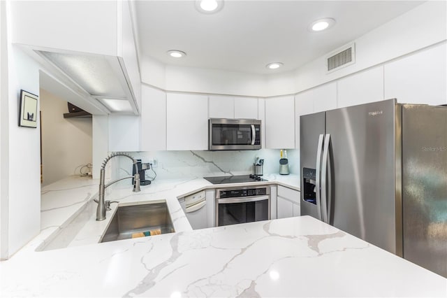 kitchen featuring decorative backsplash, sink, light stone countertops, white cabinetry, and appliances with stainless steel finishes