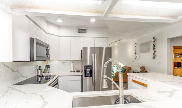 kitchen with stainless steel appliances, white cabinets, sink, and backsplash