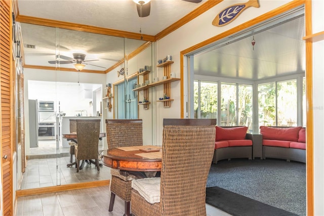 dining room with a textured ceiling, light colored carpet, ceiling fan, and crown molding