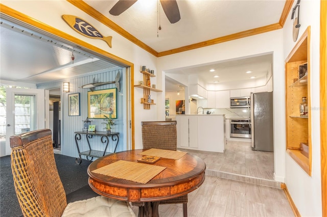 dining area with ornamental molding, light wood-type flooring, sink, and ceiling fan