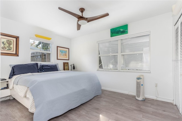 bedroom with a closet, light hardwood / wood-style floors, and ceiling fan