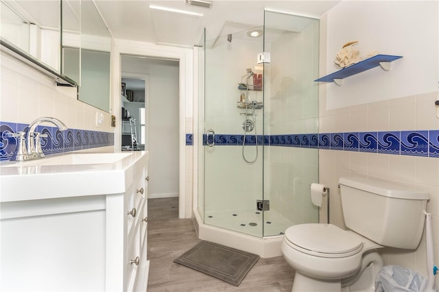 bathroom with toilet, tile walls, hardwood / wood-style floors, vanity, and walk in shower