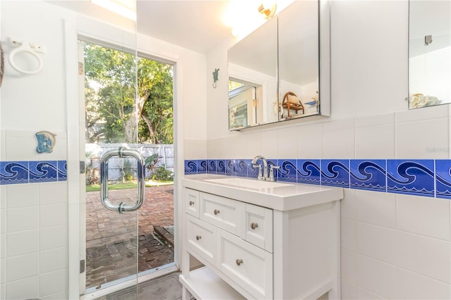 bathroom featuring a shower with door, vanity, and tile walls