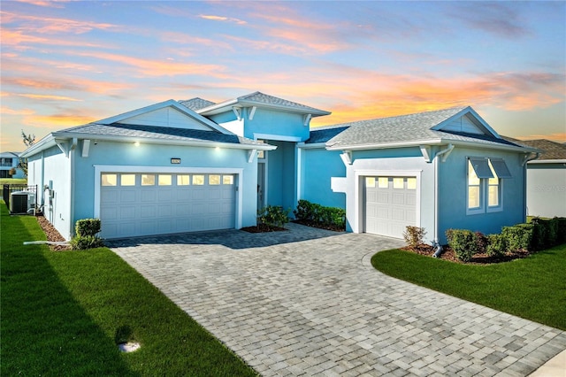 view of front facade featuring central AC, a garage, and a lawn