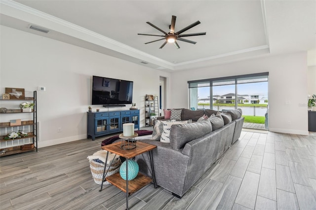 living room with a raised ceiling, ceiling fan, light hardwood / wood-style flooring, and crown molding