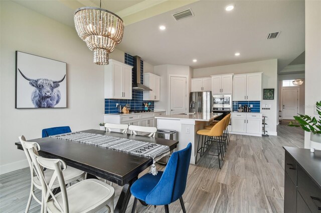 dining space with sink, light hardwood / wood-style flooring, and an inviting chandelier