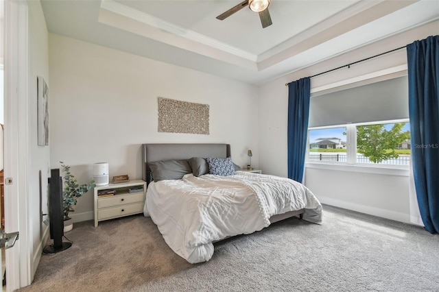 carpeted bedroom with a raised ceiling and ceiling fan