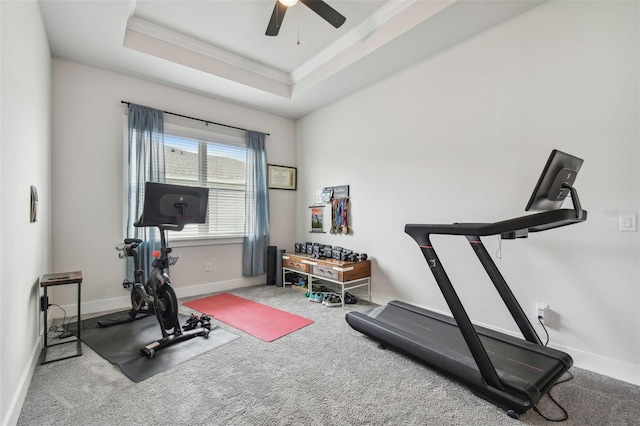 exercise area featuring a tray ceiling, ceiling fan, crown molding, and carpet flooring