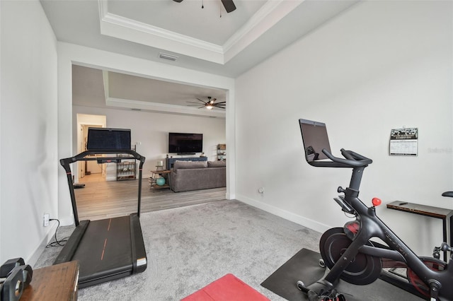 workout room featuring ceiling fan, light hardwood / wood-style floors, crown molding, and a tray ceiling