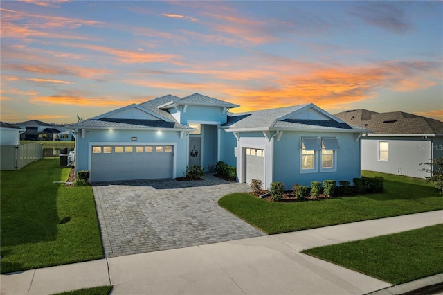 view of front facade featuring a garage, cooling unit, and a lawn