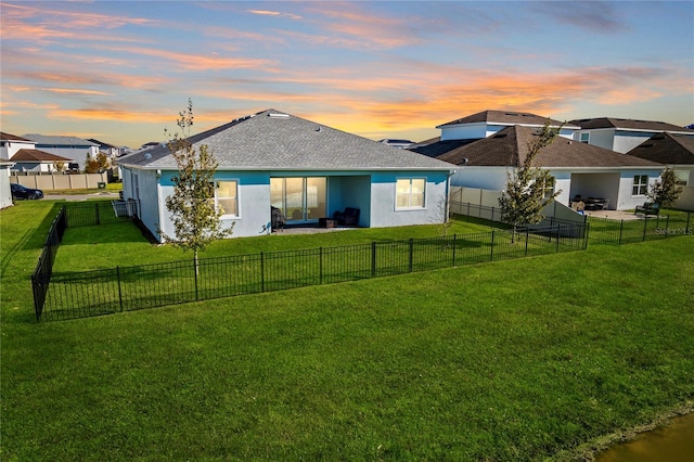 back house at dusk with a lawn