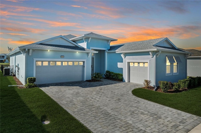 view of front of house featuring a yard, central AC, and a garage