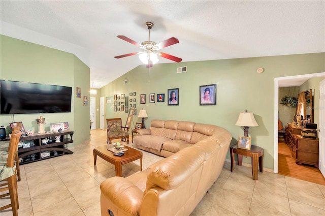 living room featuring vaulted ceiling, a textured ceiling, light tile patterned flooring, and ceiling fan