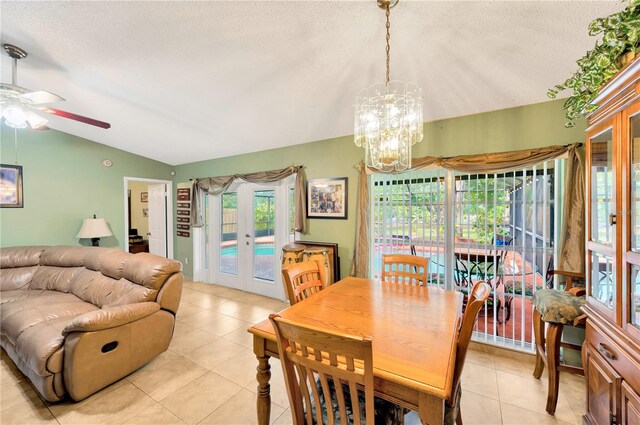 tiled dining room with lofted ceiling, french doors, a textured ceiling, and ceiling fan with notable chandelier