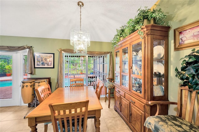 dining area featuring light tile patterned flooring, a notable chandelier, and a textured ceiling