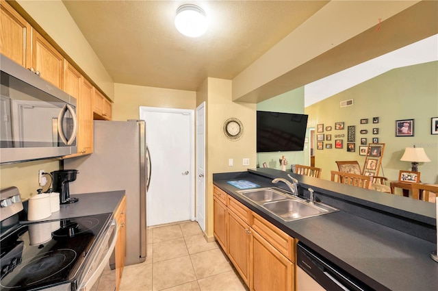 kitchen featuring sink, appliances with stainless steel finishes, vaulted ceiling, and light tile patterned flooring