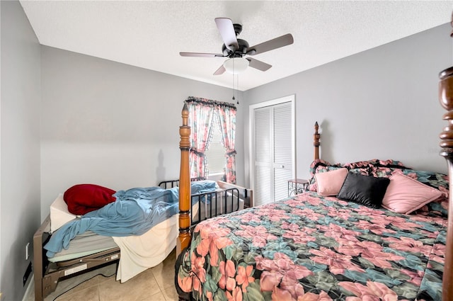 tiled bedroom with a closet, a textured ceiling, and ceiling fan