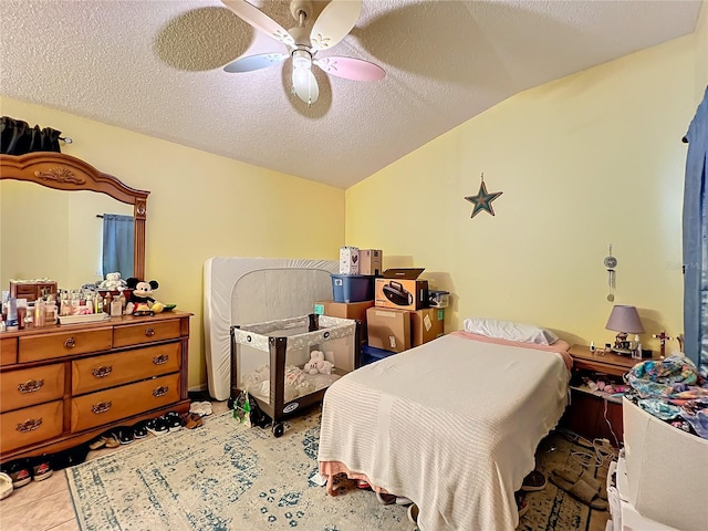 bedroom with vaulted ceiling, a textured ceiling, light tile patterned floors, and ceiling fan