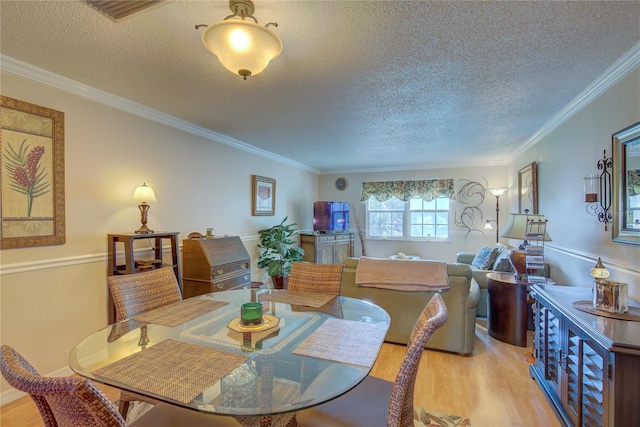 dining area featuring crown molding, light hardwood / wood-style flooring, and a textured ceiling