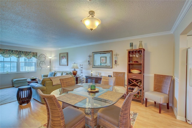 dining space featuring ornamental molding, light hardwood / wood-style flooring, and a textured ceiling