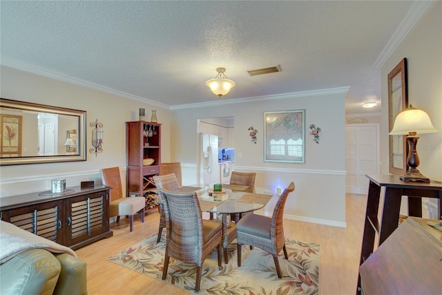 dining area featuring a textured ceiling, light hardwood / wood-style flooring, and ornamental molding