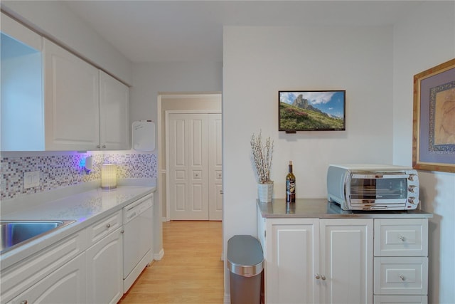 kitchen with decorative backsplash, white dishwasher, sink, light wood-type flooring, and white cabinets