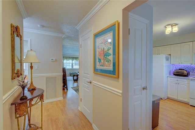 corridor with crown molding, a textured ceiling, and light hardwood / wood-style floors