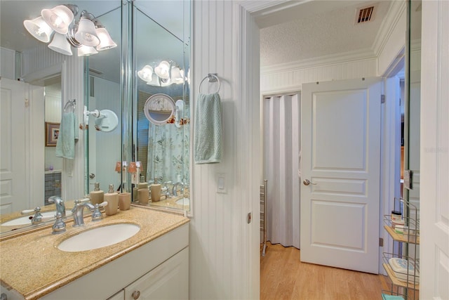 bathroom with vanity, hardwood / wood-style floors, crown molding, and a textured ceiling