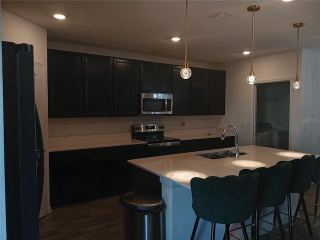 kitchen featuring dark hardwood / wood-style floors, stainless steel appliances, sink, pendant lighting, and washing machine and dryer