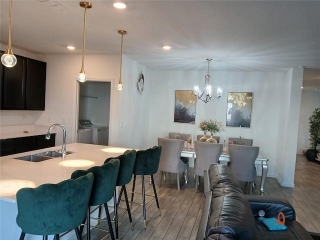 interior space with light hardwood / wood-style floors, an inviting chandelier, sink, and washing machine and clothes dryer