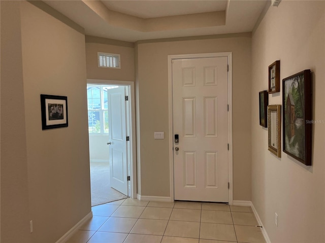 interior space with light tile patterned floors and a tray ceiling