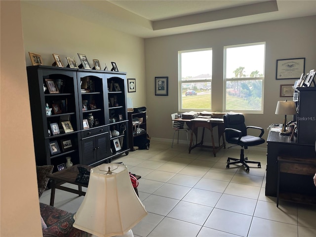 office area with a raised ceiling and light tile patterned floors