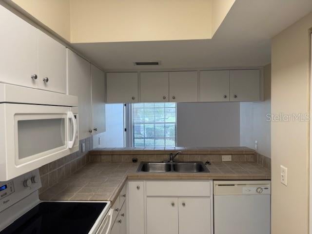 kitchen with tile countertops, white cabinetry, sink, and white appliances