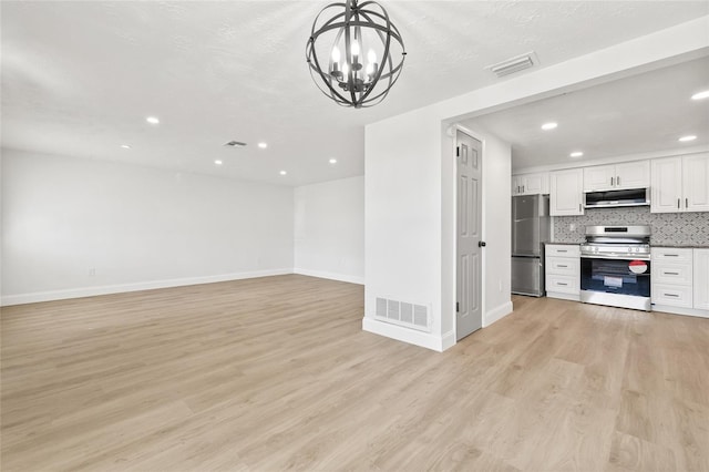 kitchen featuring an inviting chandelier, backsplash, white cabinetry, light wood-type flooring, and appliances with stainless steel finishes