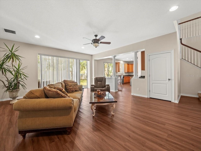 living room featuring a textured ceiling, ornate columns, dark hardwood / wood-style floors, and ceiling fan