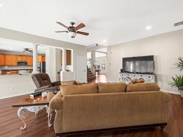 living room featuring dark wood-type flooring, ceiling fan, and decorative columns