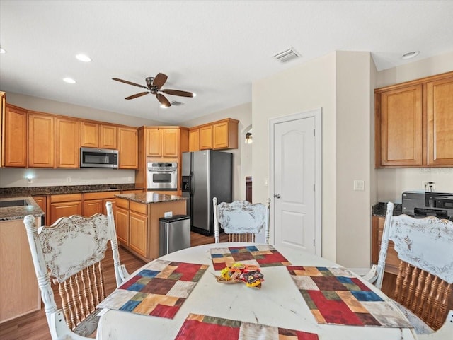 kitchen featuring ceiling fan, dark hardwood / wood-style floors, appliances with stainless steel finishes, and a kitchen island