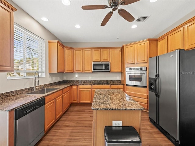 kitchen with sink, a center island, ceiling fan, stainless steel appliances, and hardwood / wood-style flooring