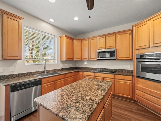 kitchen featuring sink, a kitchen island, a textured ceiling, stainless steel appliances, and dark wood-type flooring