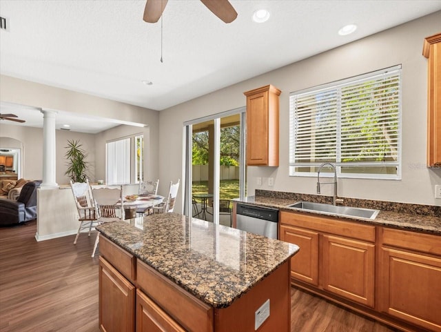 kitchen featuring stainless steel dishwasher, sink, ornate columns, and dark hardwood / wood-style flooring